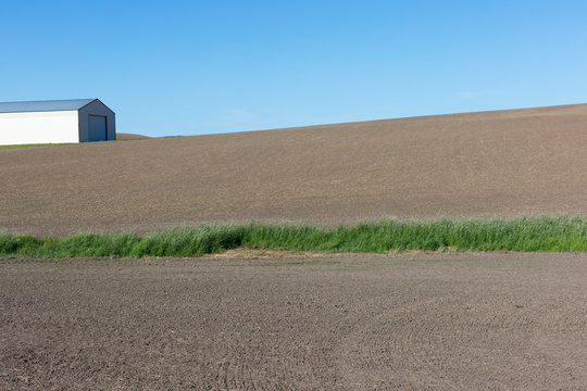 View of farmland and barn in fallow field