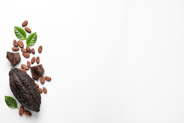 Cocoa pod with beans and chocolate pieces on white background, top view