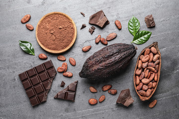 Flat lay composition with cocoa pods and chocolate on grey table