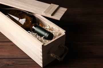 Open wooden crate with bottle of wine on table