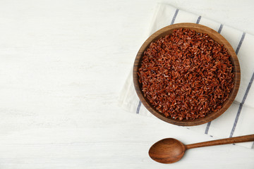 Flat lay composition with delicious cooked brown rice on white wooden table. Space for text