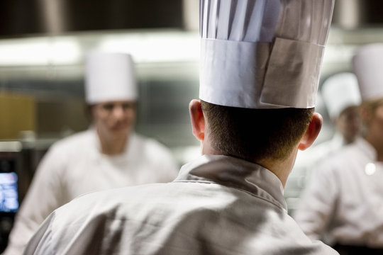 Rear view of chef wearing toque hat in commercial kitchen