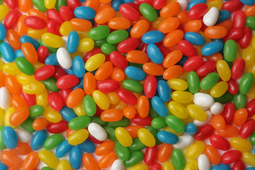 Tasty bright jelly beans as background, top view