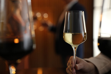 Woman with glass of wine in restaurant, closeup. Space for text