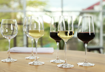 Glasses with different wines on table against blurred background