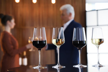 Glasses of different wines on table against blurred background