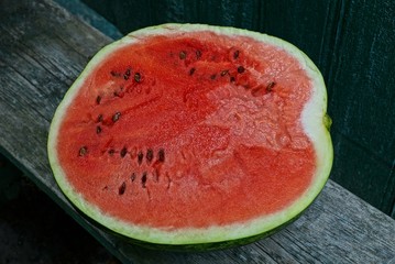 a large piece of red ripe watermelon lies on a gray table board