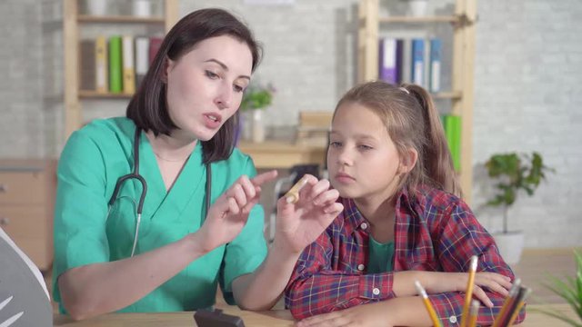 Doctor otolaryngologist explains the hearing impaired teenager about the hearing aid c