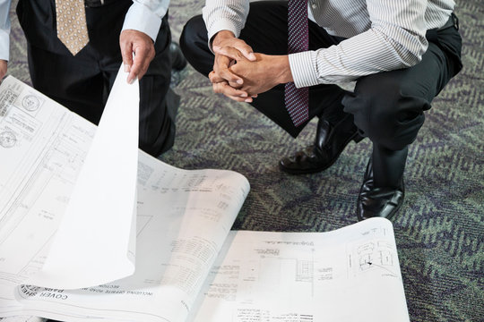 Low section of business people holding blueprint