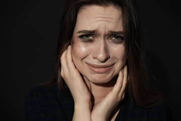 Crying young woman on dark background. Stop violence