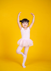 Portrait of little asian child girl dreams of becoming ballerina in a pink tutu skirt isolated on...
