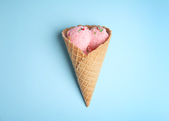 Delicious ice cream in wafer cone on blue background, top view