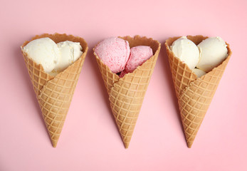 Delicious ice creams in wafer cones on pink background, flat lay