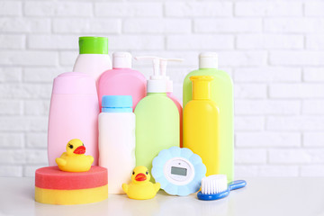 Baby accessories on table near white brick wall