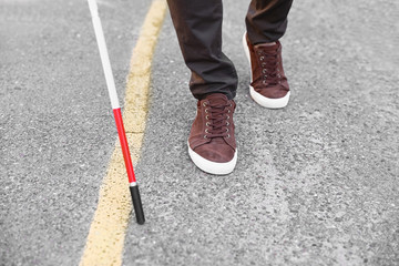 Blind person with cane crossing road, closeup