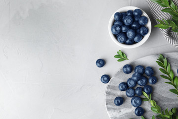 Flat lay composition with tasty blueberries on grey table, space for text