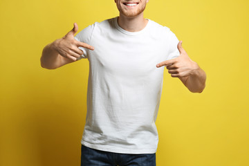 Young man wearing blank t-shirt on yellow background, closeup. Mockup for design - obrazy, fototapety, plakaty
