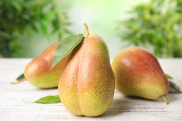 Ripe juicy pears on white wooden table against blurred background