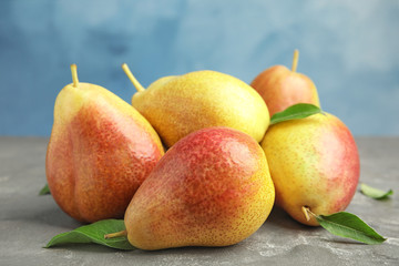 Heap of ripe juicy pears on grey stone table against blue background