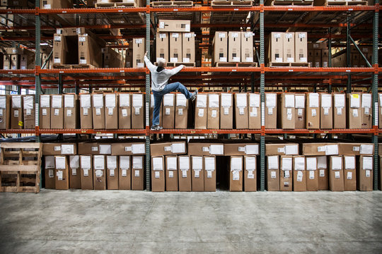 Worker trying to climb rack of products in warehouse