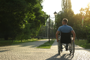 Man in wheelchair at park on sunny day. Space for text