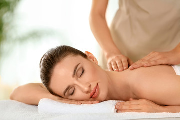 Fototapeta na wymiar Beautiful young woman enjoying massage in spa salon