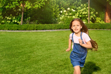 Fototapeta premium Cute little girl running in green park on summer day