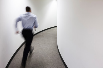 Businessman running in office corridor