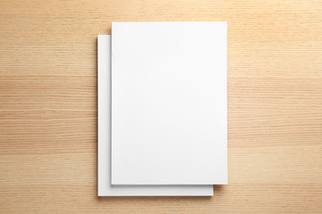 Stack of blank paper sheets for brochure on wooden background, top view. Mock up