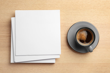 Obraz na płótnie Canvas Blank paper sheets for brochure and cup of coffee on wooden background, flat lay. Mock up