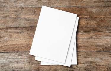 Stack of blank paper sheets for brochure on wooden background, top view. Mock up - Powered by Adobe