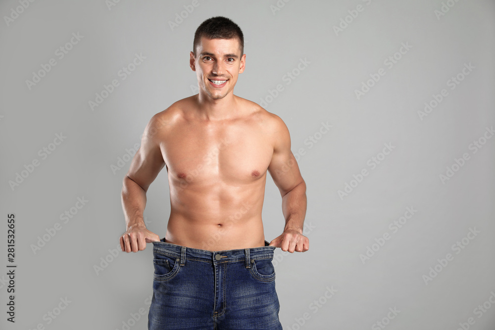 Poster Young man with slim body in old big size jeans on grey background