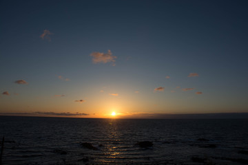 Fototapeta na wymiar 静かな海の水平線に沈む夕陽