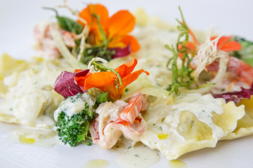 A portion of ravioli in the plate decorated with edible flowers