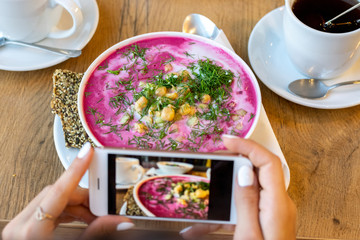Food eating, technology, culinary and people concept - woman hands with smartphone photographing soup at restaurant