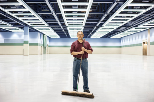 Portrait of man standing with broom at convention center