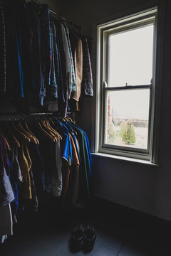 Interior view of wardrobe with clothes and sash window