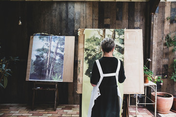 Rear view of senior woman painting on canvas