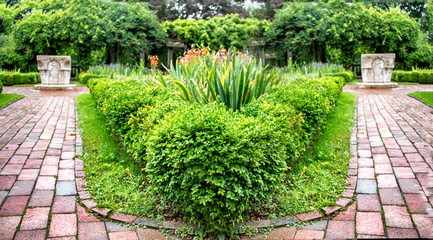 stone path with bushes leading up to a mansion