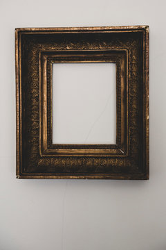 Close up of empty gilded antique picture frame on white wall