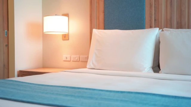 Pan of luxury hotel bed with white sheets, pillows and a blue runner