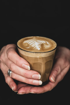 Close up of woman's hand holding glass of latte