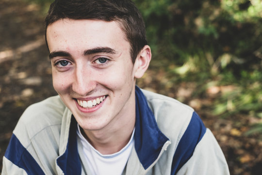 Portrait of smiling teenage boy sitting in forest