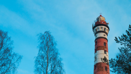 Naklejka premium Lighthouse in the forest among the trees. red and white lighthouse