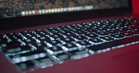 Fototapeta na wymiar Close-up of modern computer keyboard illumination. Slow motion view laptop screen and backlit keyboard keys. Technology.