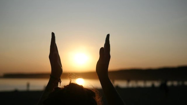 Close up female hands clap their hands on the background the sunset sky with sun