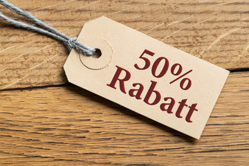 Hangtag mit Aufschrift "50% Rabatt" auf Holzhintergrund