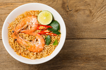 Instant noodles, spicy shrimp soup, spicy, spicy, with Thai spices placed on an old wooden table.