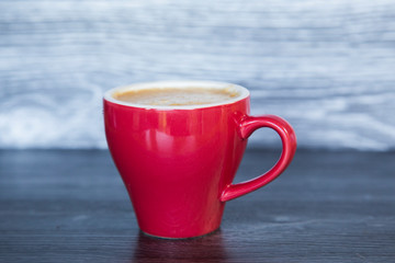 Homemade espresso flat white in bright red cup on dark wood background. Perfect with a chocolate biscuit. Feelings of warmth, luxury, reward. Contrast with red, wood and rich chocolate. Tantalising.
