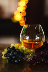 French grape brandy, strong alcoholic drink. Still life. Glass of cognac and bunch of grapes. Service and tasting concept. 